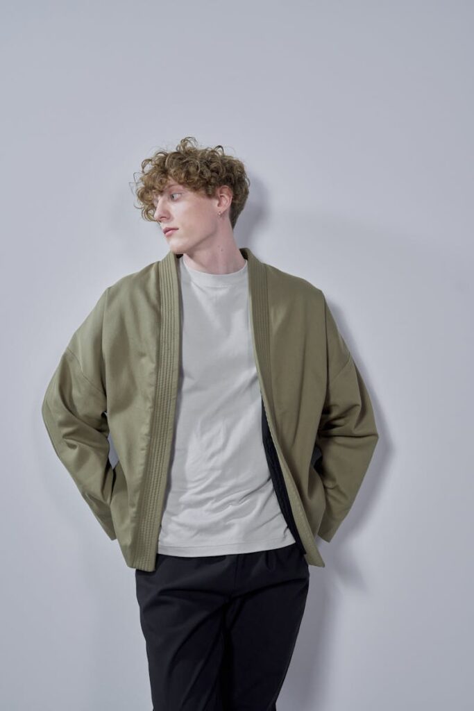 Young man in casual fashion posing against a gray studio background.