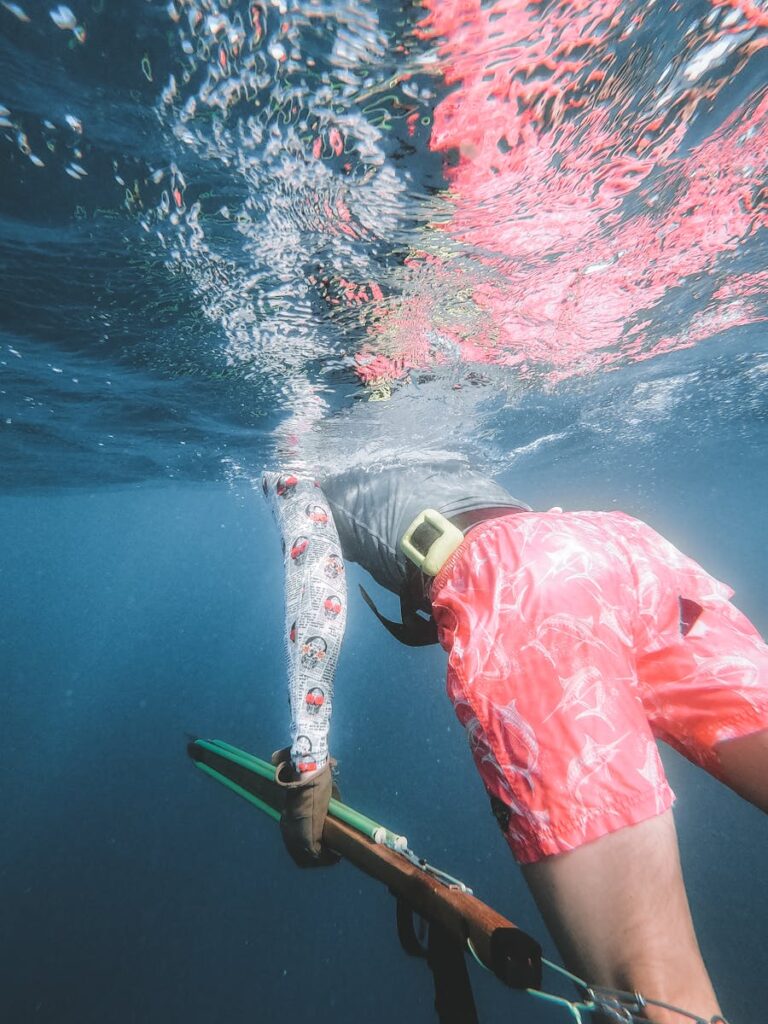 A vibrant underwater scene of a diver spearfishing, showcasing dynamic movement and reflection.