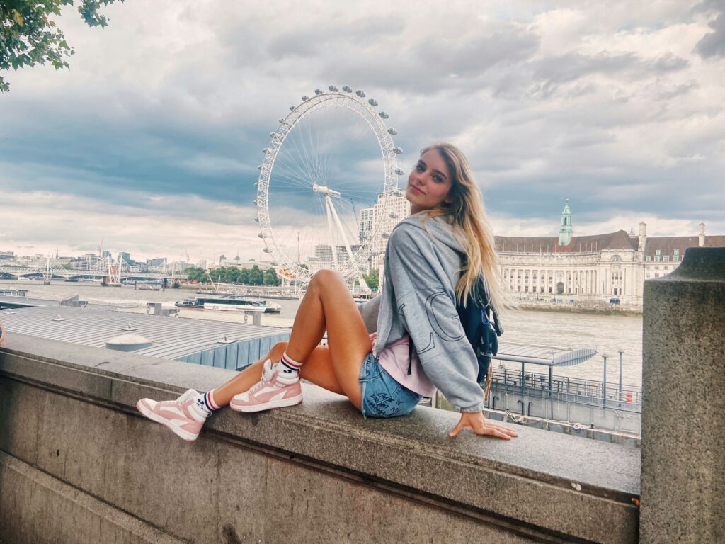 A woman sitting on a ledge looking at the sky