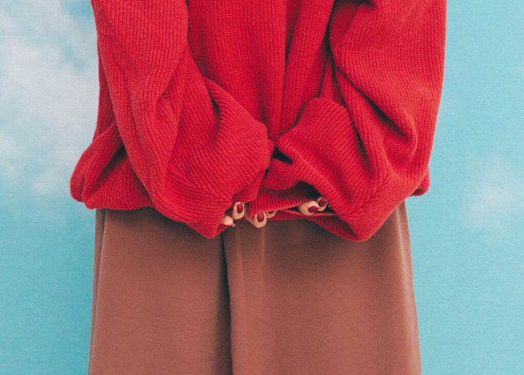 A woman wearing a red sweater and brown pants