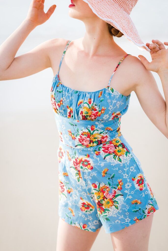 woman wearing blue floral rompers and brown hat