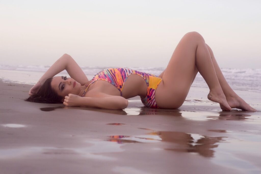 woman in pink and white bikini lying on the beach