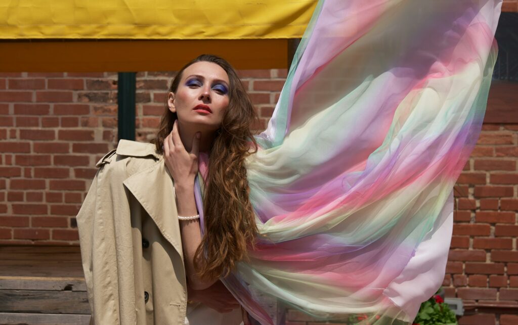 a woman holding a colorful scarf in front of a brick building