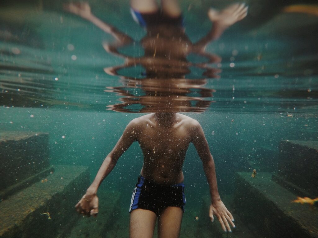 man swimming in body of water
