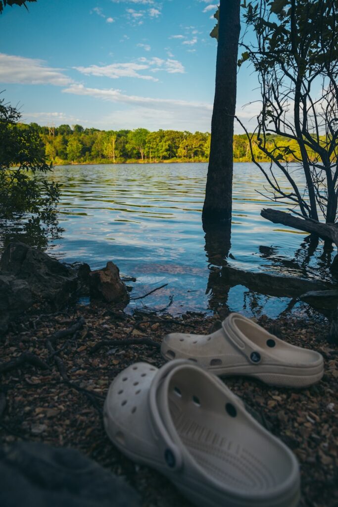 A pair of shoes sitting on the shore of a lake