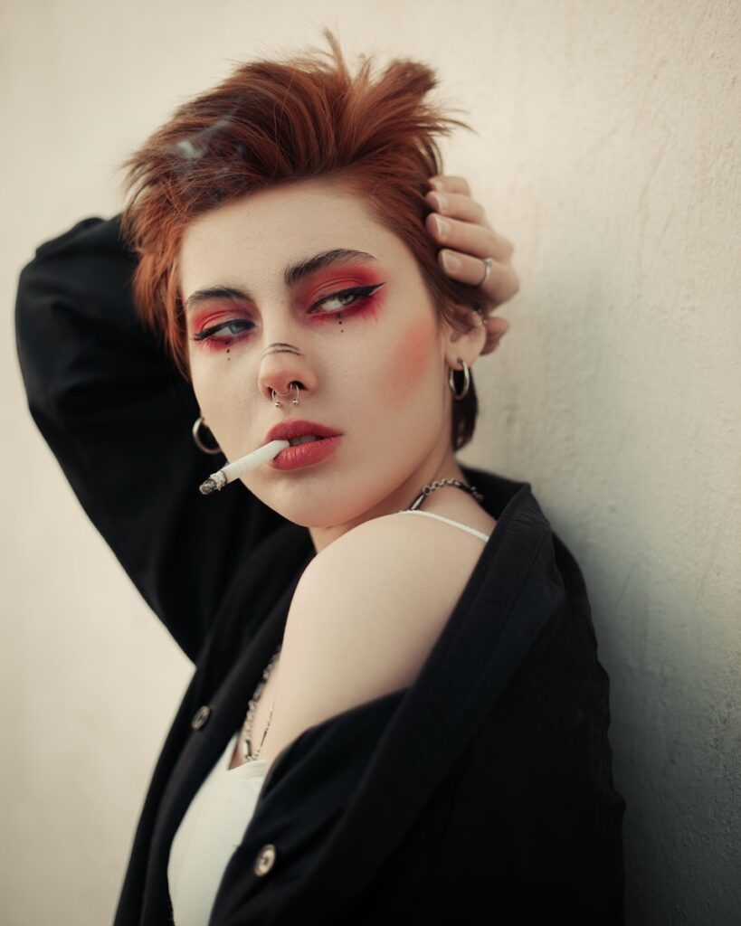 a woman with a cigarette in her mouth leaning against a wall