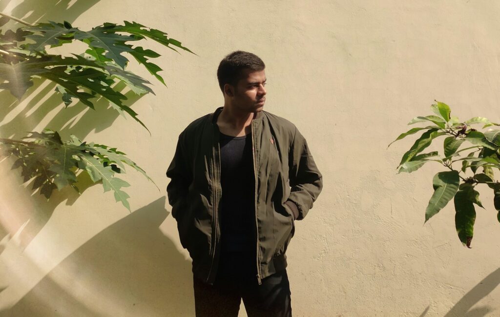 man in black leather jacket standing beside green plant