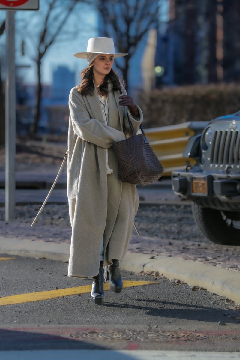 Fashionable woman in a gray coat and fedora walks in NYC street.