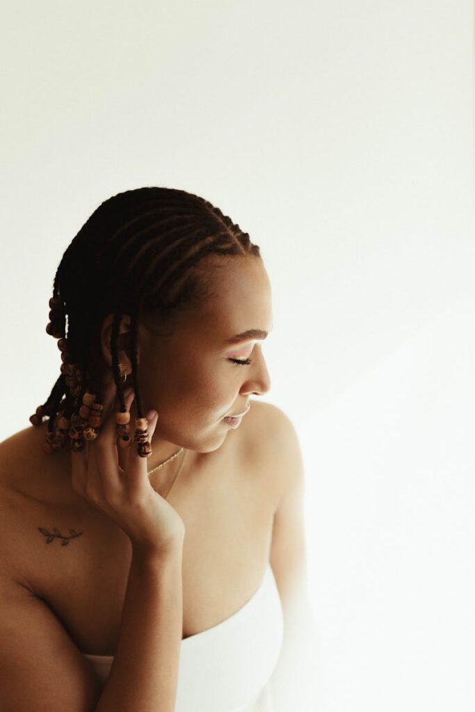 A stylish studio portrait showcasing a woman with braided hair and subtle makeup.