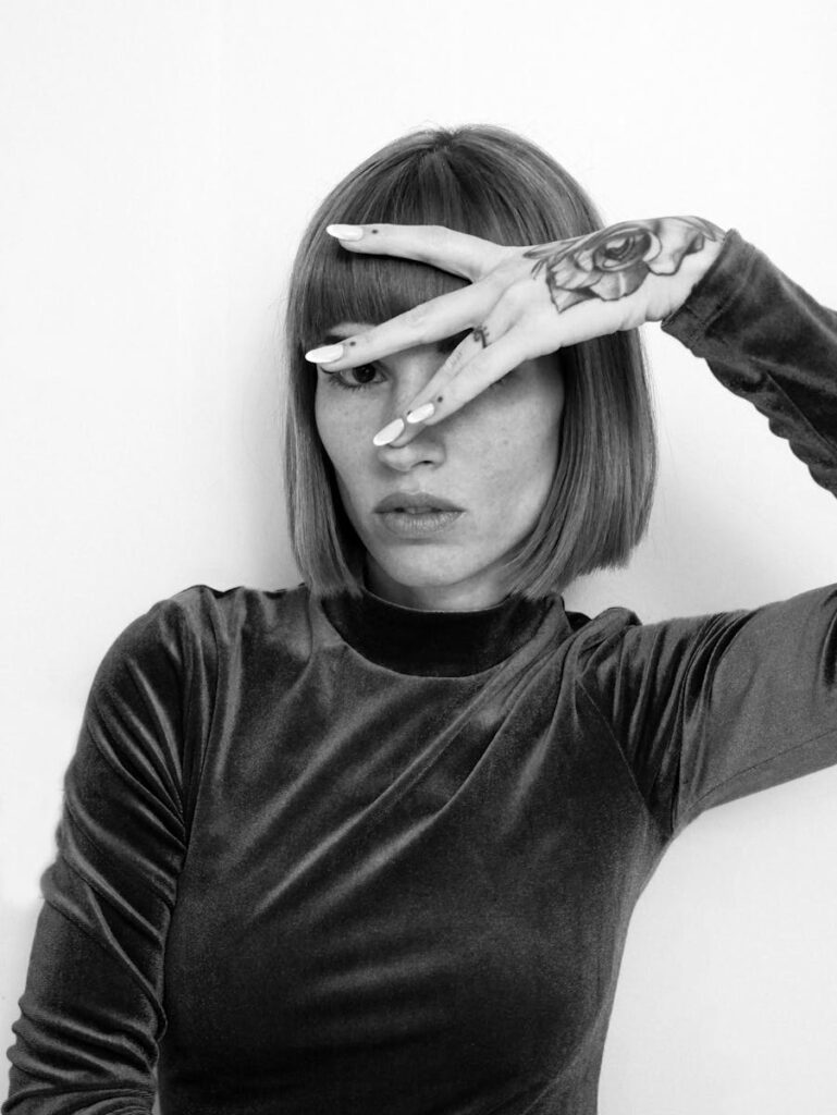 Artistic black and white portrait featuring a tattooed woman in a stylish pose.