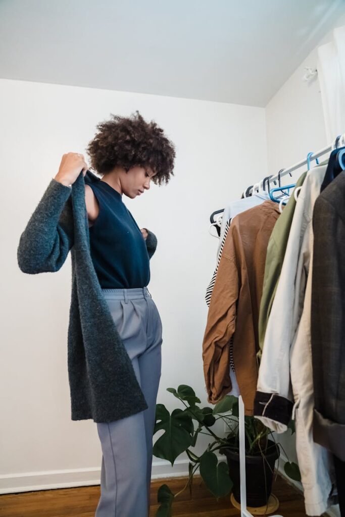 African American woman selecting clothes from a wardrobe, trying on a coat.