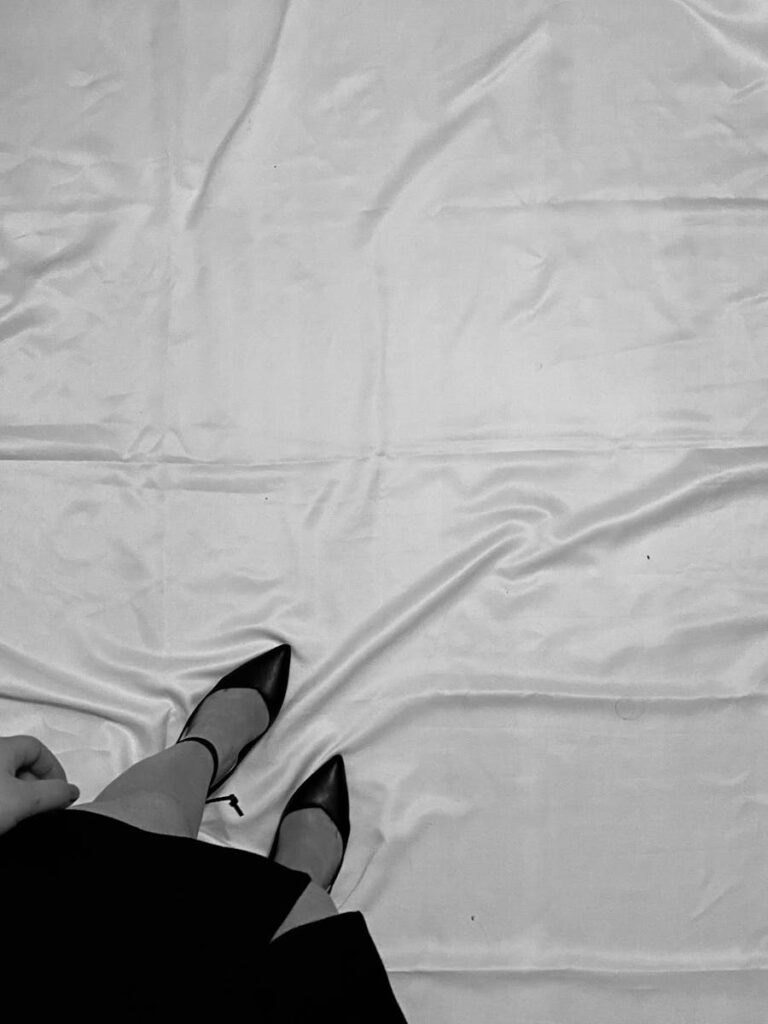 Black high heels on wrinkled white fabric, creating a monochrome fashion statement.