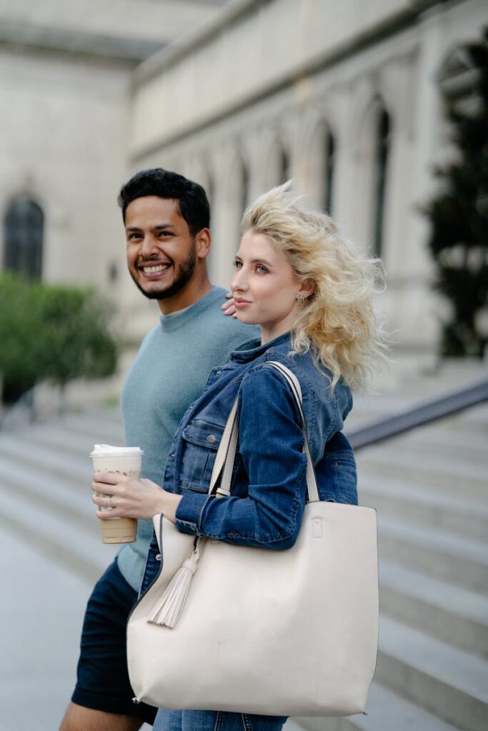 Happy couple walking together outdoors holding coffee cups, enjoying a pleasant day.