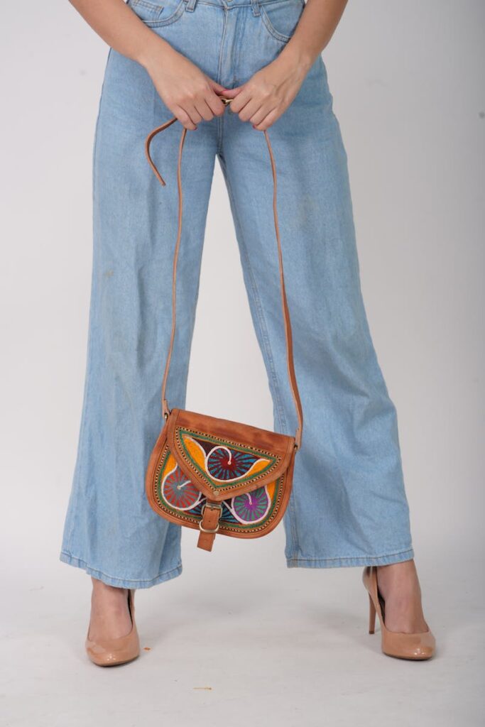 Stylish outfit featuring wide-leg denim and vibrant sling bag with heels.