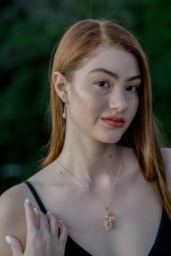 Portrait of an elegant redhead woman wearing a stylish necklace, outdoors.