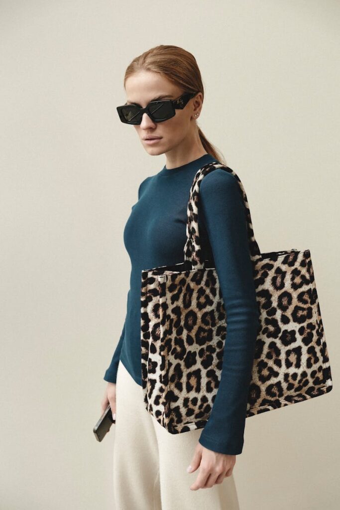 Fashionable woman in sunglasses with leopard print tote in Paris.