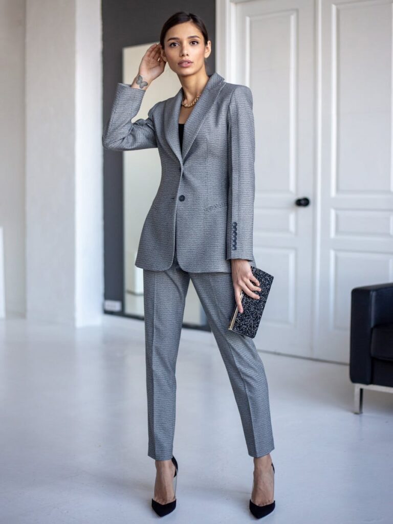 Elegant woman in a gray suit poses indoors with a confident expression, embodying modern business style.