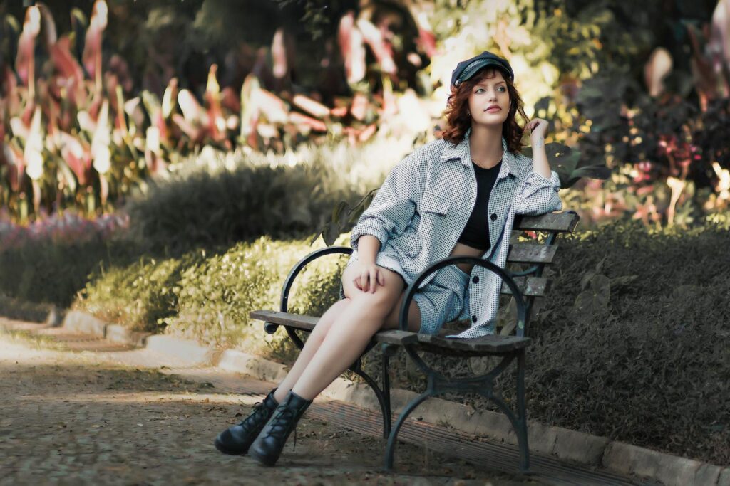 Woman in casual outfit sitting on a bench in a vibrant garden, enjoying a peaceful moment.