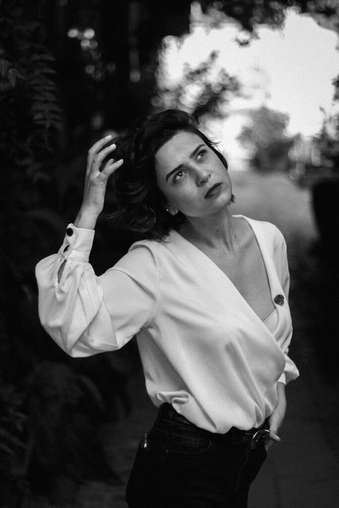 Striking black and white portrait of a woman posing outdoors with hand in hair.
