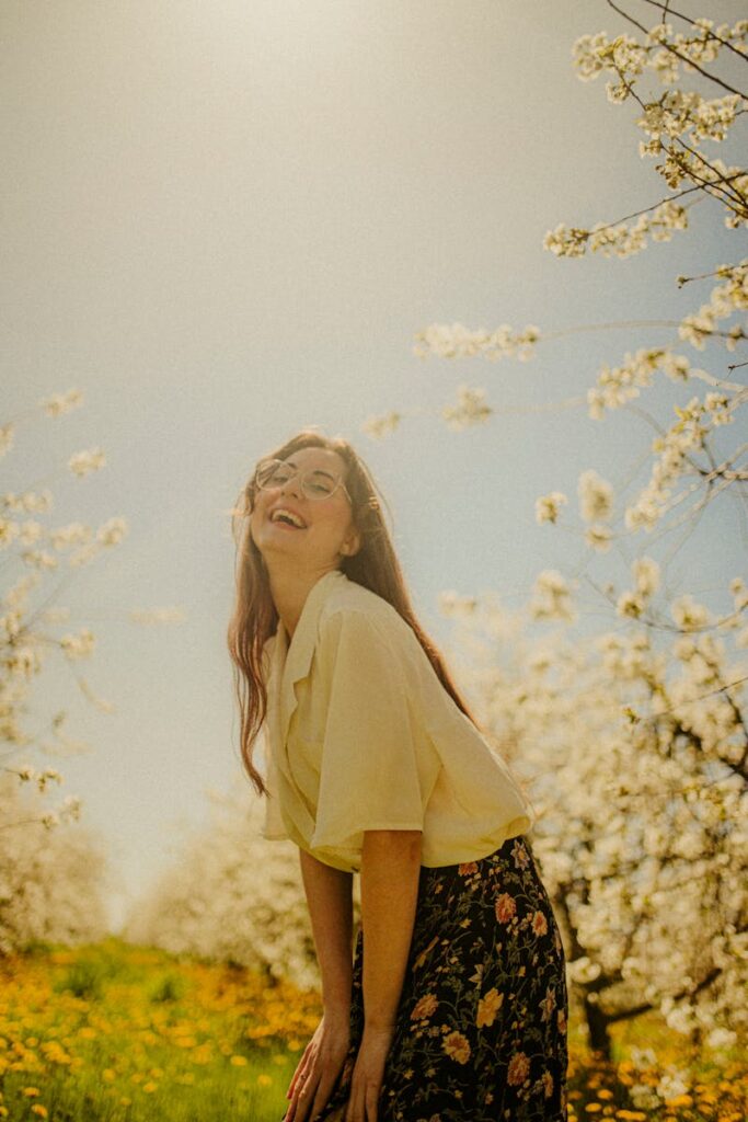 Smiling woman enjoying a sunny day in a blooming orchard, capturing the essence of spring.