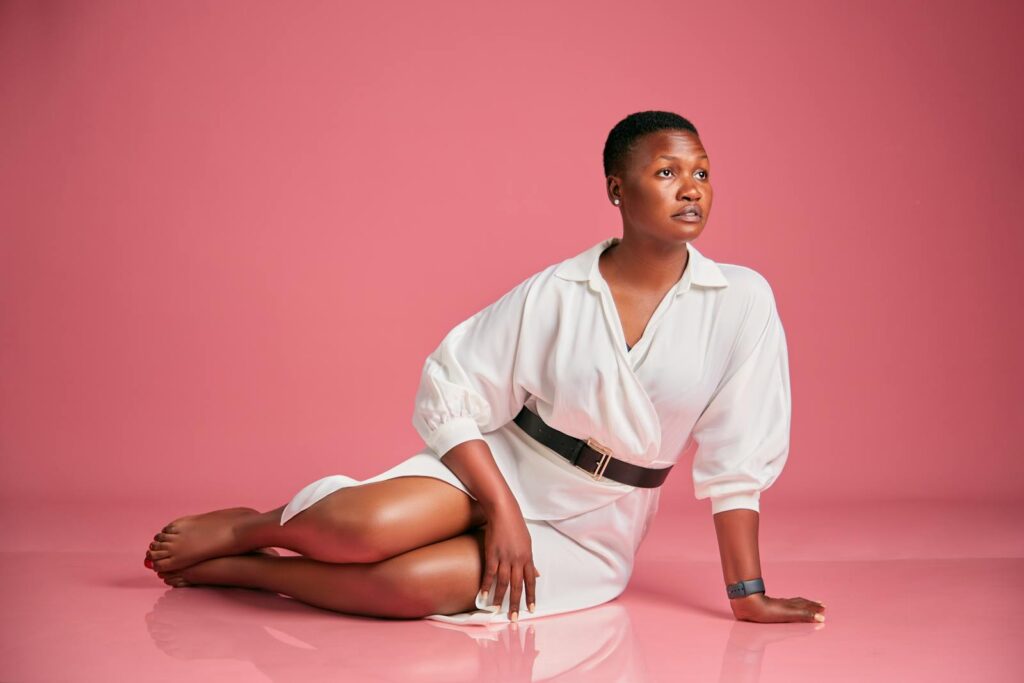 Stunning studio portrait of a woman in elegant fashion against a pink background.
