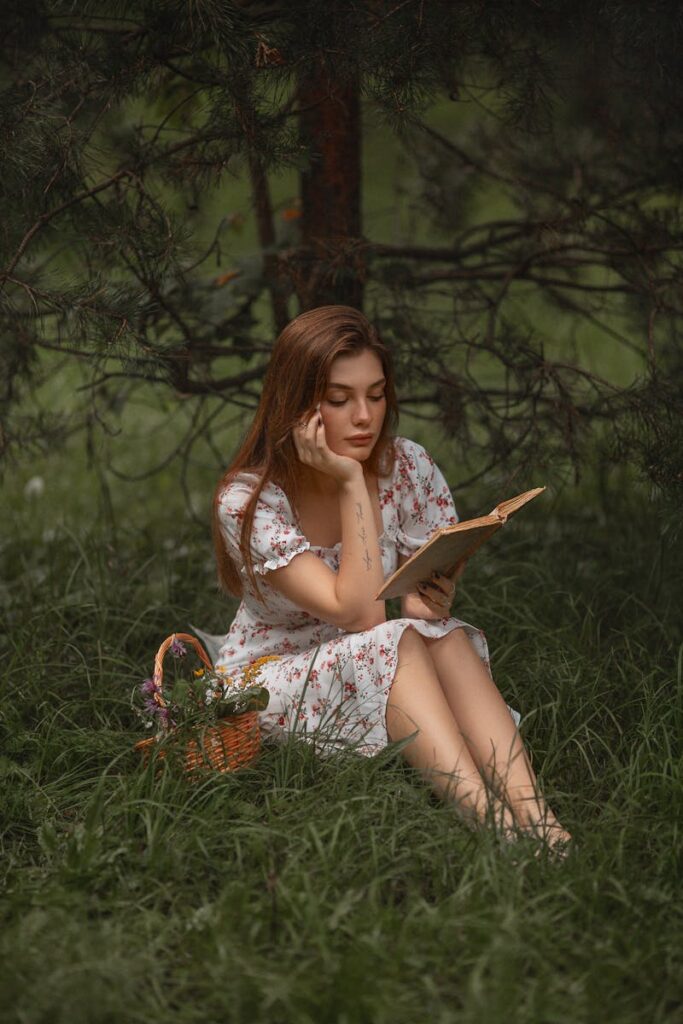 Young woman reading a book in the serene outdoors, symbolizing relaxation and summer recreation.