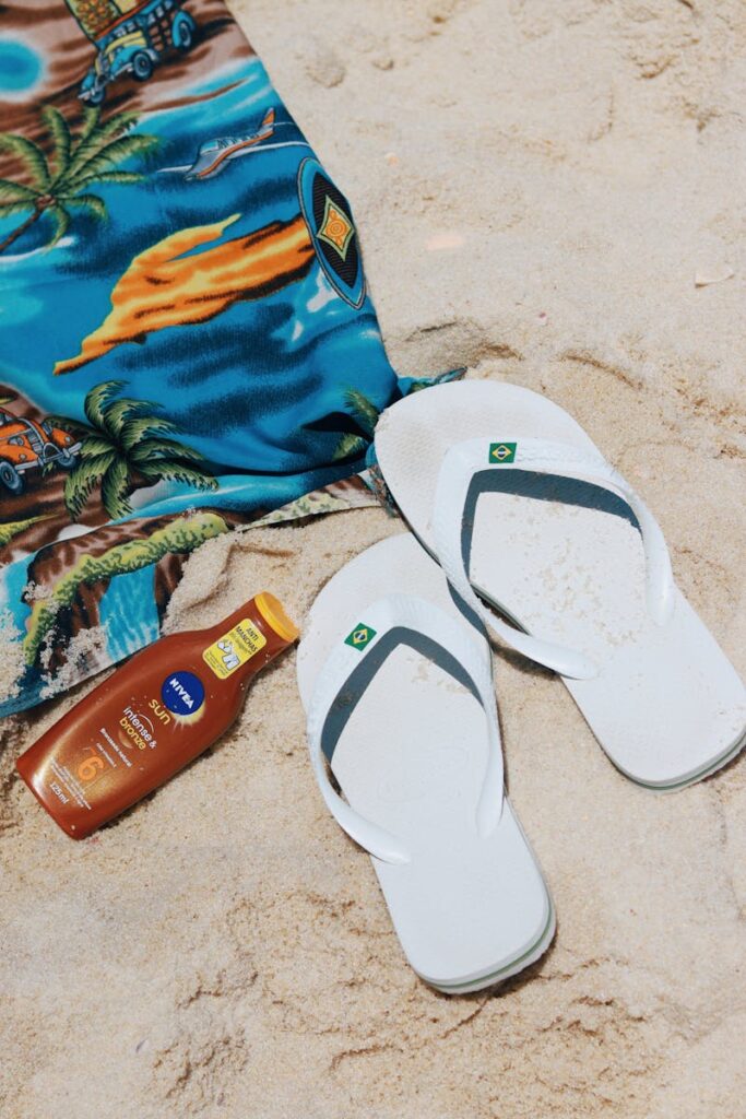 Flip-flops, sunscreen, and a towel on a sunny Rio beach.
