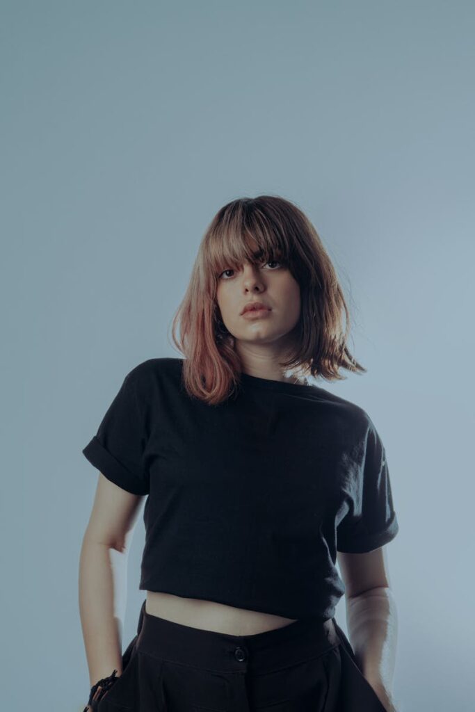 Stylish young woman in a black crop top posing confidently indoors.