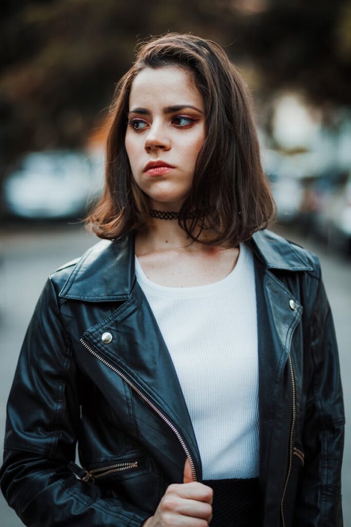 Young woman in a leather jacket looking away, showcasing urban fashion style.