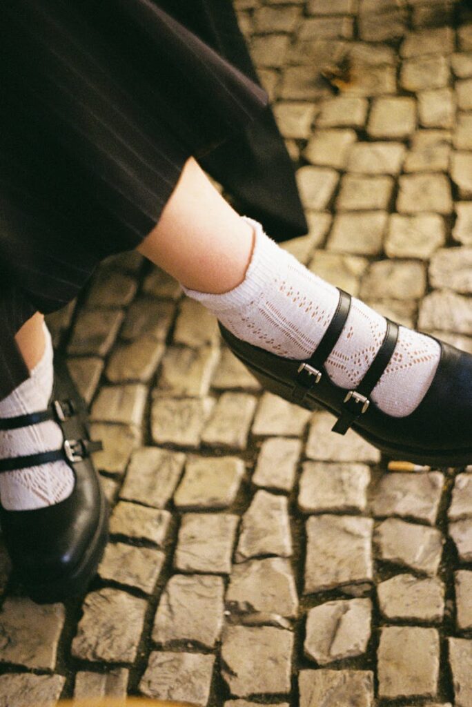 Double-buckled Mary Jane shoes with white socks on Lisbon cobblestones - a classic fashion look.