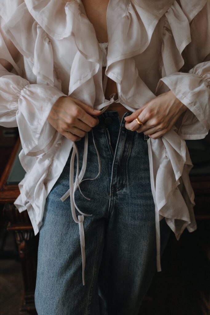Fashion shot of a woman zipping high-waisted jeans, showcasing style and elegance.