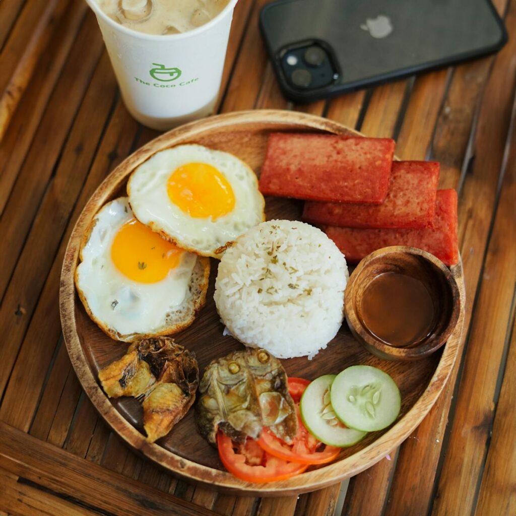 Enjoy a classic Filipino breakfast featuring eggs, rice, and luncheon meat served with iced coffee.