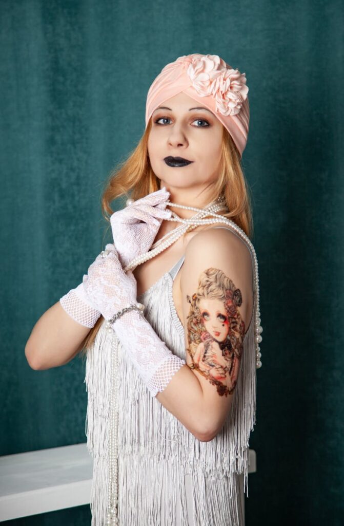 Stylish woman in vintage attire showcasing a detailed arm tattoo.
