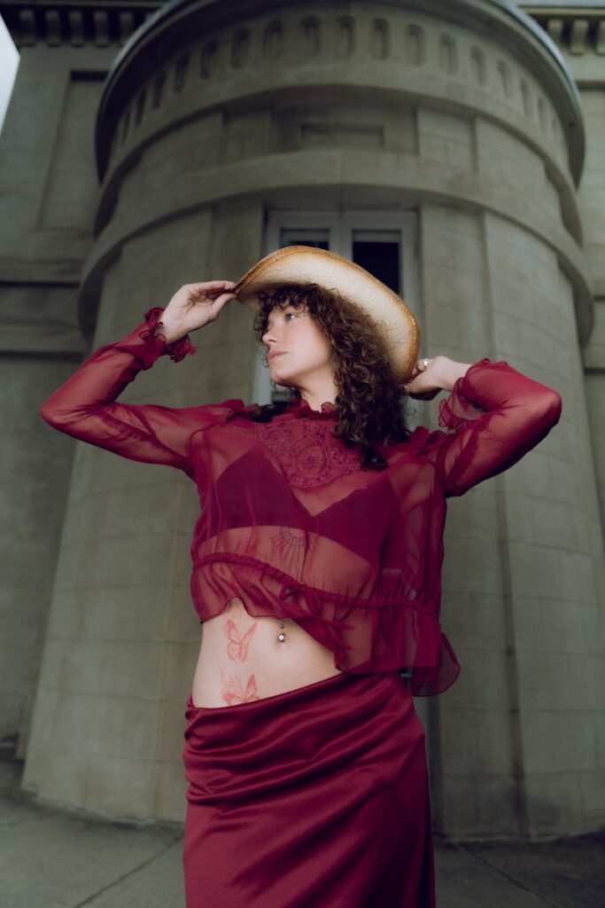 Fashion model in burgundy outfit poses near an urban structure. Hamilton, ON.