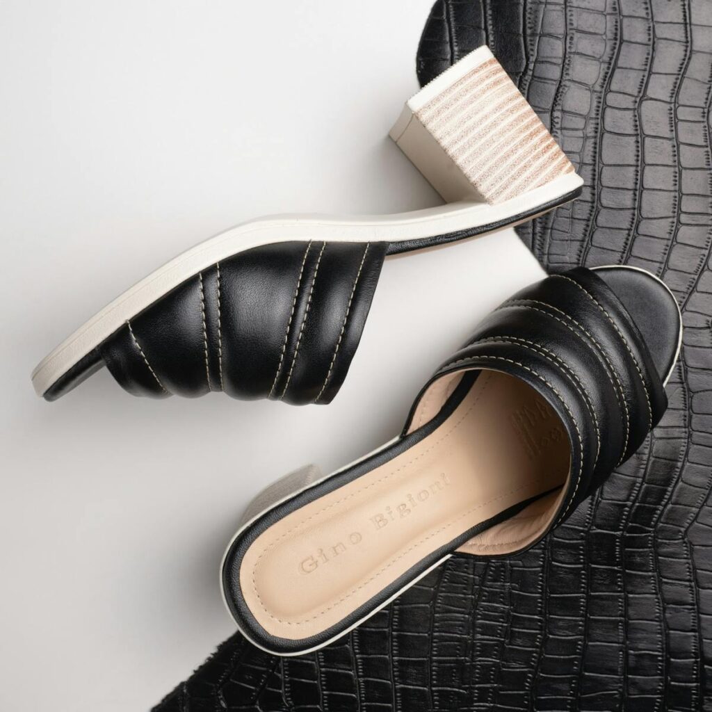 Stylish black leather heeled sandals with a textured background for fashion and luxury appeal.