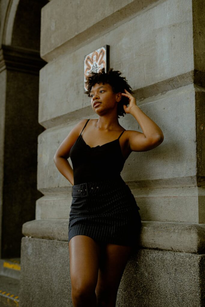 Portrait of a fashionable black woman standing confidently against an urban wall.