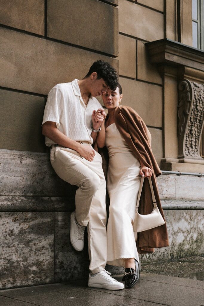A fashionable couple in neutral tones sharing an intimate moment outdoors.
