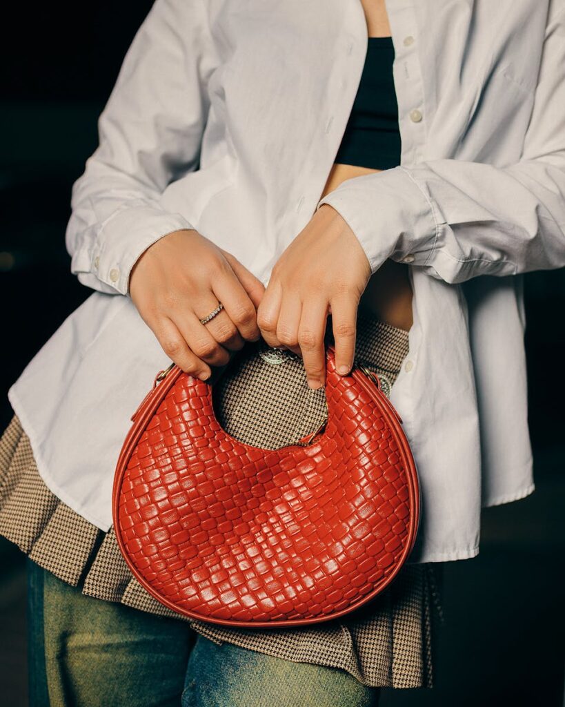 Stylish woman in casual outfit holding a red woven handbag outdoors.