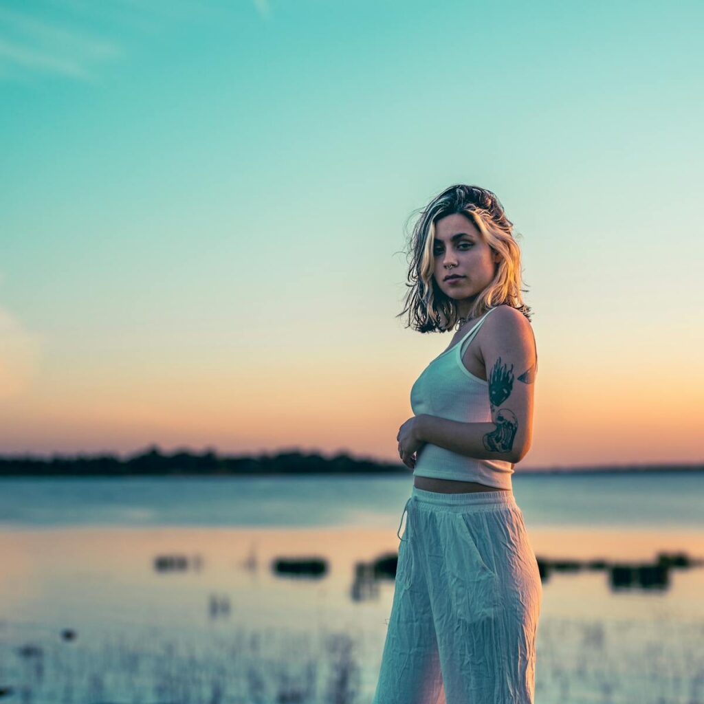 A calm sunset portrait featuring a woman with tattoos by Chascomús Lake, capturing serene and dreamy tones.