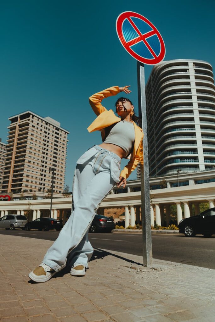 Stylish woman poses near a modern building in Baku, Azerbaijan, under a clear blue sky.
