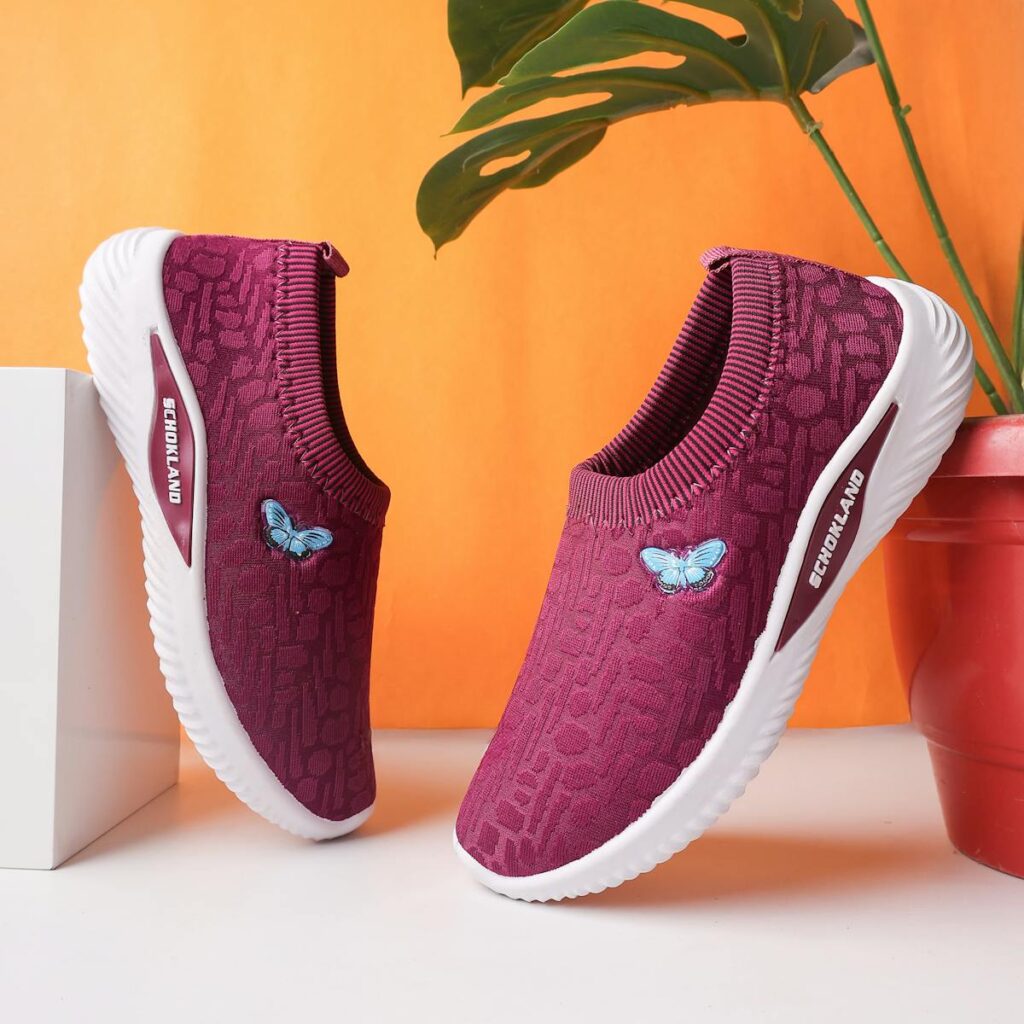 Elegant purple sneakers with butterfly embroidery on an orange backdrop, perfect for a vibrant lifestyle.