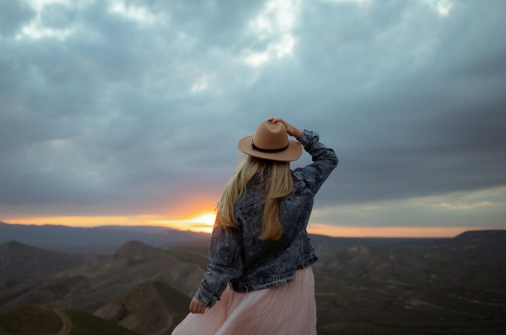 Woman in a hat overlooks a breathtaking sunset in Koktebel, evoking a sense of freedom and tranquility.