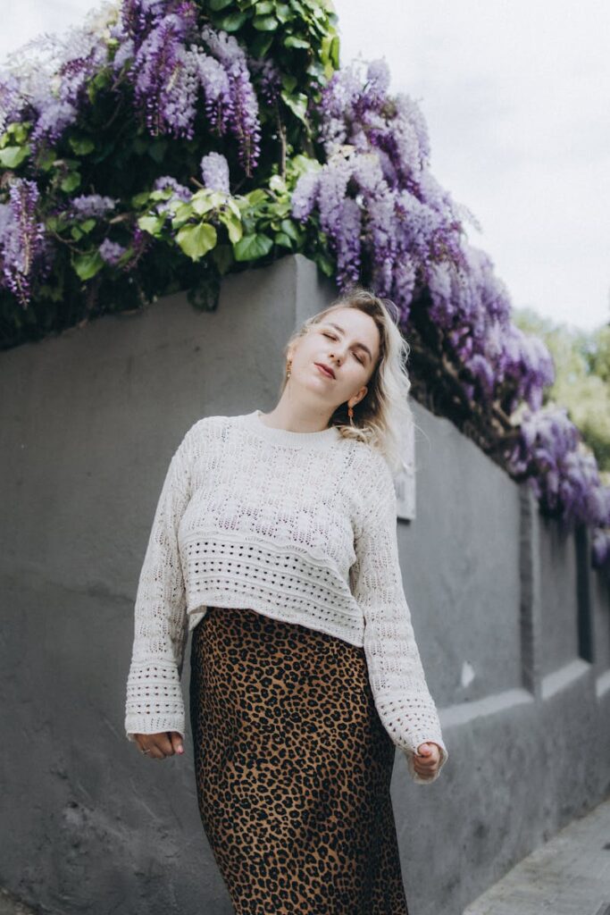 Young woman in a sweater enjoying a spring day by a flowering wisteria bush.