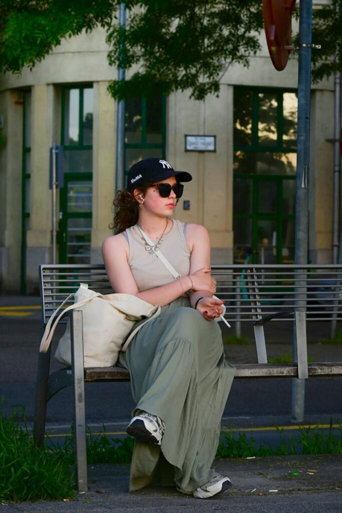 Woman in casual fashion sitting on bench in New York City street, capturing urban lifestyle.