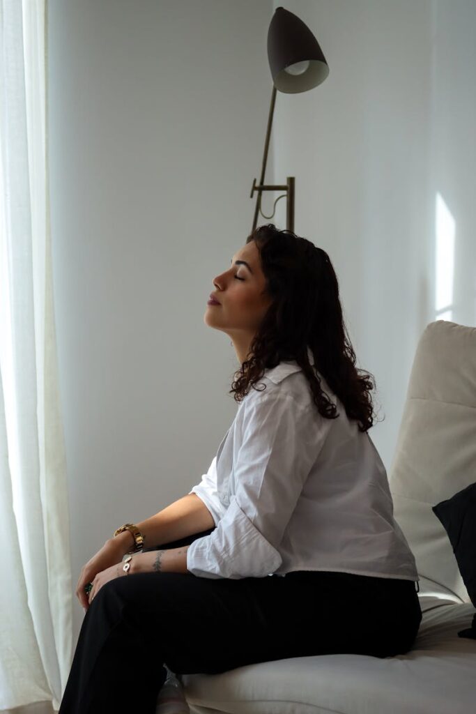 Side profile of a relaxed woman sitting indoors in sunlight.