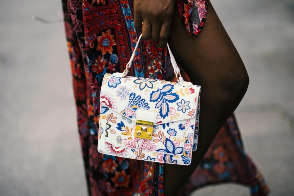 Close-up of a stylish floral handbag held by a fashionable individual in a trendy outfit.