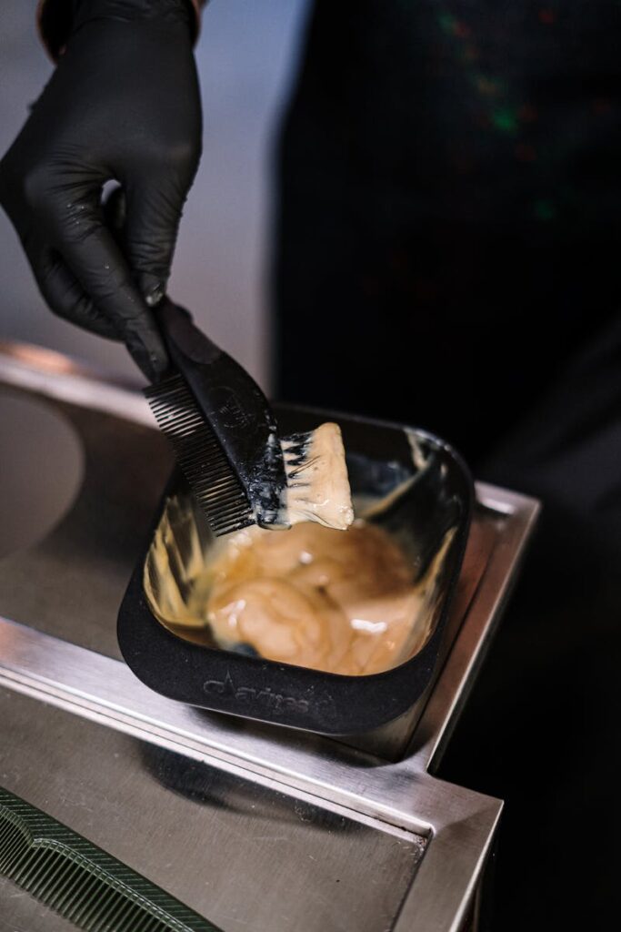 Close-up of stylist mixing hair dye with black brush in salon environment.
