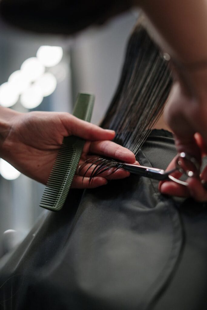 Close-up of hairstylist cutting wet hair in a salon.