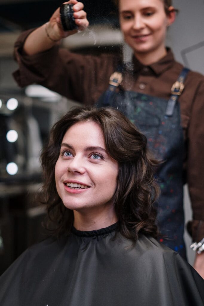 Smiling woman getting her hair styled at a salon by a professional hairdresser.
