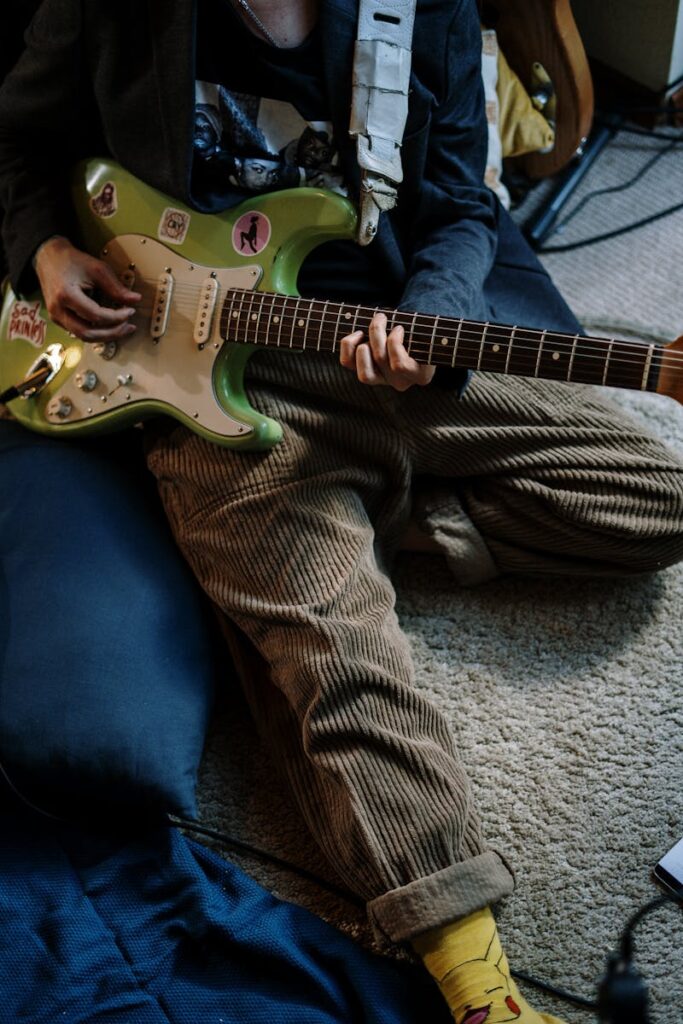 A detailed shot of a musician playing an electric guitar indoors, capturing a relaxed lifestyle.